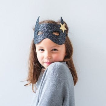 Channel her inner superhero with this fabulously glittery bat mask!  Made from the chunkiest, sparkliest black glitter and with a lovely gold star detail, this super-cool elasticated mask will be sure to make her stand out from the crowd! 